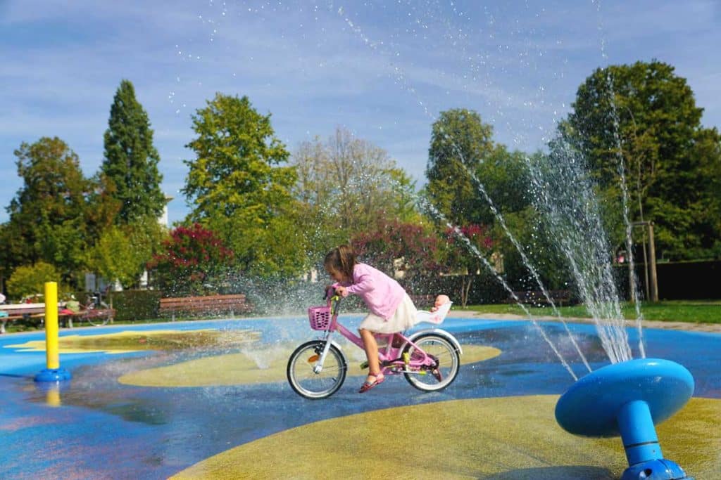Petite fille traversant des jeux d'eau à vélo